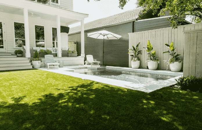 Bright landscaping idea with an outdoor pool, white and green tones