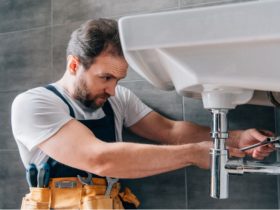 Plumber is fixing sink in bathroom