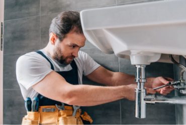 Plumber is fixing sink in bathroom
