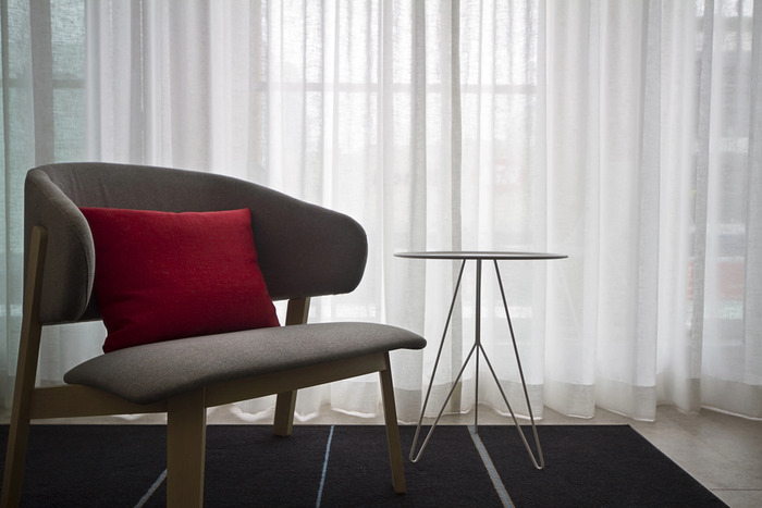 Inside the room a grey chair and sheer curtain