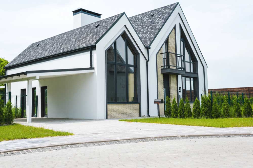  A new modern and luxury home with windows small front yard with grass.