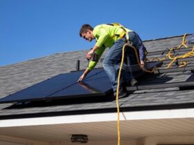 A worker installing solar panels on a building roof using safety gear