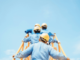 Construction workers in safety gear climbing scaffolding under a clear blue sky, symbolizing teamwork and improved workplace conditions.