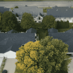 Aerial view of suburban homes with new dark-colored roofs, representing property value improvement through roofing investment.