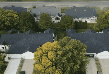 Aerial view of suburban homes with new dark-colored roofs, representing property value improvement through roofing investment.