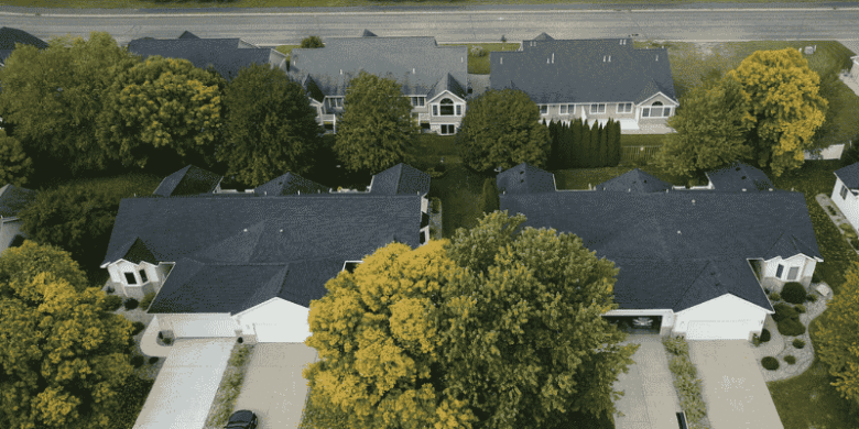 Aerial view of suburban homes with new dark-colored roofs, representing property value improvement through roofing investment.