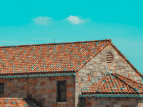 Close-up view of a house with red tile roofing under a bright blue sky, representing quality roof installation and contractor expertise.