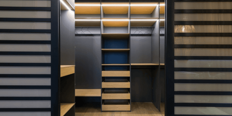 A modern walk-in closet featuring built-in shelves, drawers, and hanging space with integrated lighting.
