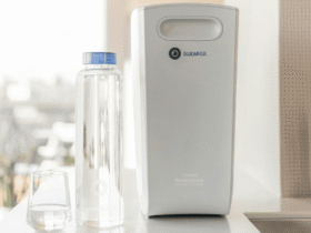 Compact home water filtration system placed on a kitchen counter beside a sink and reusable bottle, representing cleaner water and reduced household waste.